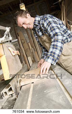 A carpenter sawing wood in a workshop View Large Photo Image Picture - A carpenter sawing wood in a workshop. Fotosearch