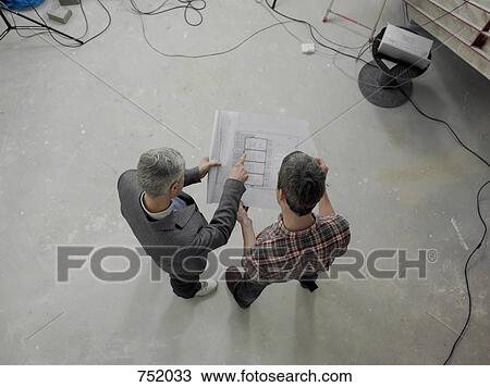 Stock Image - A construction worker going over blueprints with an architect. Fotosearch