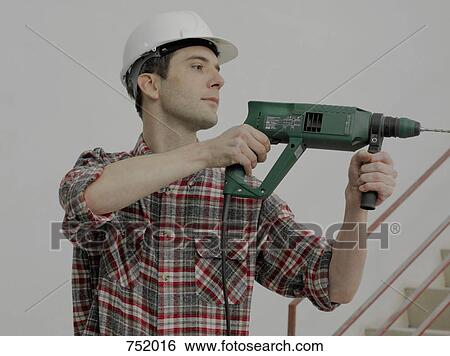A construction worker using a drill on a wall View Large Photo Image Stock Photograph - A construction worker using a drill on a wall. Fotosearch