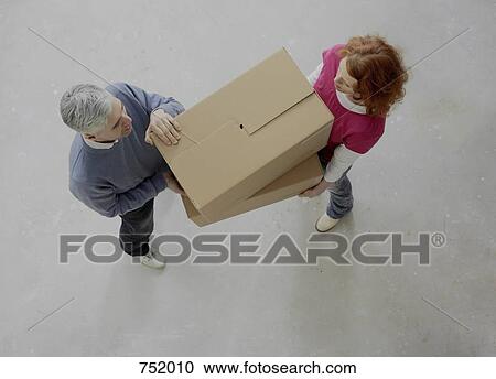 Stock Image - A couple carrying boxes together. Fotosearch