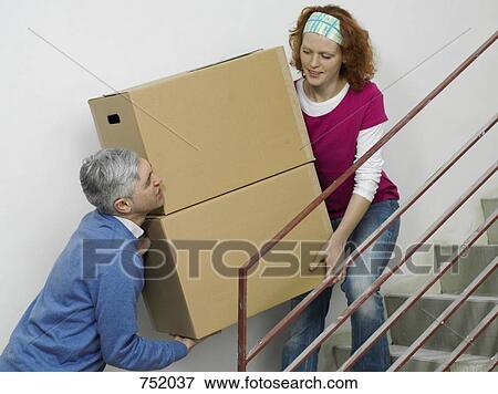 Stock Photo - A couple carrying boxes together up stairs. Fotosearch