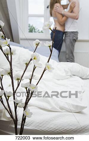 Stock Image - A couple embracing in their bedroom. Fotosearch