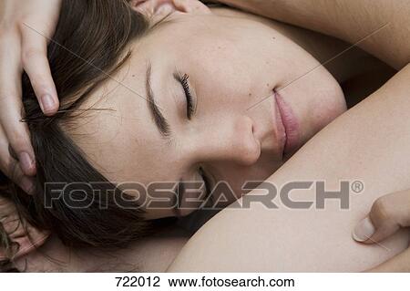 Stock Image - A couple lying down and embracing. Fotosearch