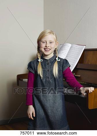 A little girl posing next to a piano View Large Photo Image Stock Image - A little girl posing next to a piano. Fotosearch