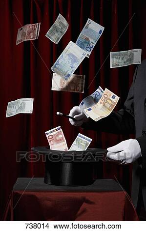 A magician performing magic by making money come out of a hat View Large Photo Image Picture - A magician performing magic by making money come out of a hat. Fotosearch