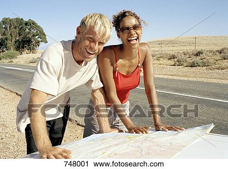 A man and a woman leaning on a car bonnet and reading a map View Large Photo Image Stock Image - A man and a woman leaning on a car bonnet and reading a map. Fotosearch