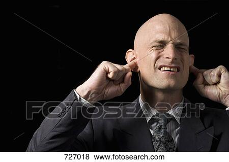 Stock Photo - A man blocking his ears with his fingers. Fotosearch