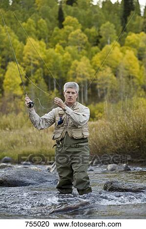Stock Image - A man fly fishing in a river. Fotosearch