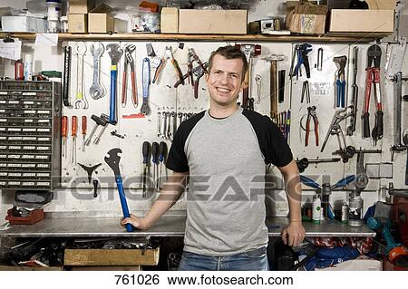 A man holding a wrench in a workshop View Large Photo Image Stock Photograph - A man holding a wrench in a workshop. Fotosearch
