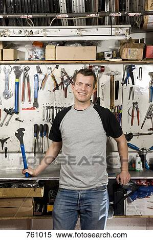 Stock Photography - A man holding a wrench in a workshop. Fotosearch