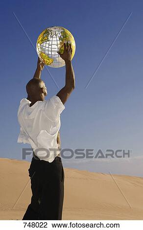 A man holding an inflatable globe in the desert View Large Photo Image Stock Image - A man holding an inflatable globe in the desert. Fotosearch
