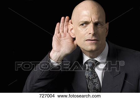Picture - A man holding his hand to his ear. Fotosearch
