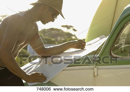 A man leaning on a car bonnet and reading a map View Large Photo Image Stock Photograph - A man leaning on a car bonnet and reading a map. Fotosearch