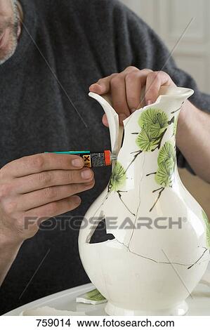 Picture - A man repairing a broken vase. Fotosearch