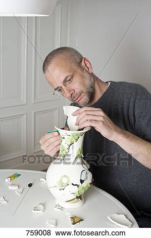 Stock Photo - A man repairing a broken vase. Fotosearch