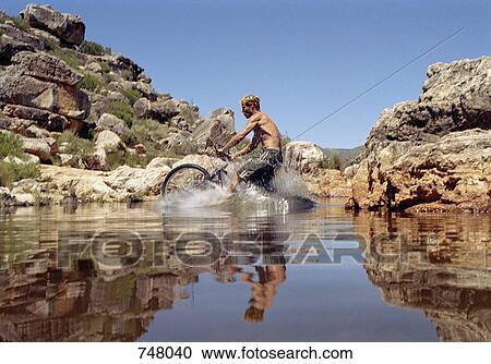 A man riding on a mountain bike through a stream View Large Photo Image Stock Image - A man riding on a mountain bike through a stream. Fotosearch
