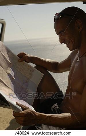 A man sitting in a car and looking at a map View Large Photo Image Picture - A man sitting in a car and looking at a map. Fotosearch