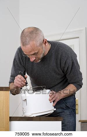 Stock Photography - A man sticking a knife in a toaster. Fotosearch