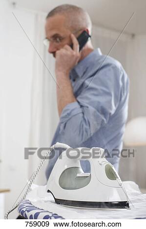 A man talking on the phone with his back to an iron which is burning his shirt View Large Photo Image Stock Photo - A man talking on the phone with his back to an iron which is burning his shirt. Fotosearch