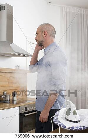 A man talking on the phone with his back to an iron which is burning his shirt View Large Photo Image Stock Photograph - A man talking on the phone with his back to an iron which is burning his shirt. Fotosearch