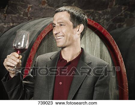 A vintner holding a glass of red wine and smiling View Large Photo Image Stock Image - A vintner holding a glass of red wine and smiling. Fotosearch