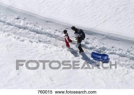 Stock Photography - A woman and a girl walking with a sled in the snow. Fotosearch