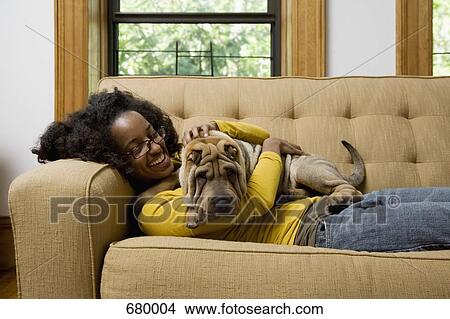 Picture - A woman lying a couch with her Shar-Pei. Fotosearch