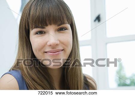 Stock Photography - A woman standing infront of a window and smiling . Fotosearch
