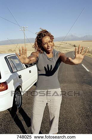 Stock Photography - A woman standing on a road with her arms outstretched. Fotosearch