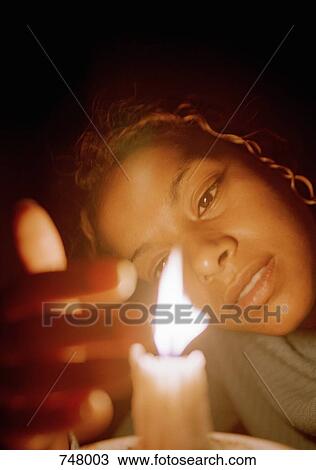 Stock Image - A woman staring at a candle. Fotosearch