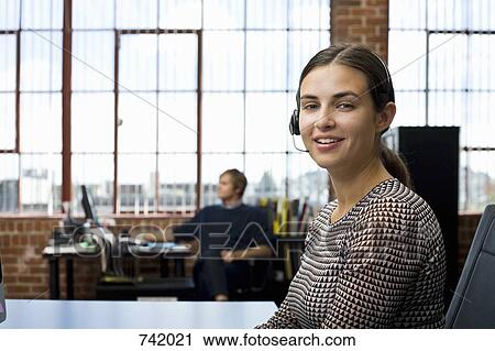 A woman wearing a headset in an office View Large Photo Image Stock Image - A woman wearing a headset in an office. Fotosearch