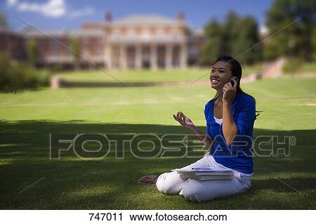 A young woman using a mobile phone on university lawn View Large Photo Image Stock Image - A young woman using a mobile phone on university lawn. Fotosearch