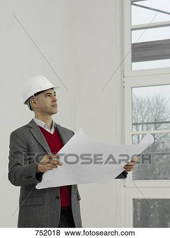 An architect reviewing work on a construction site View Large Photo Image Stock Photo - An architect reviewing work on a construction site. Fotosearch