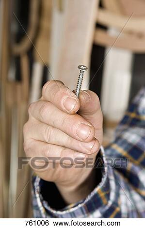 Close-up of a man holding a screw View Large Photo Image Stock Photograph - Close-up of a man holding a screw. Fotosearch