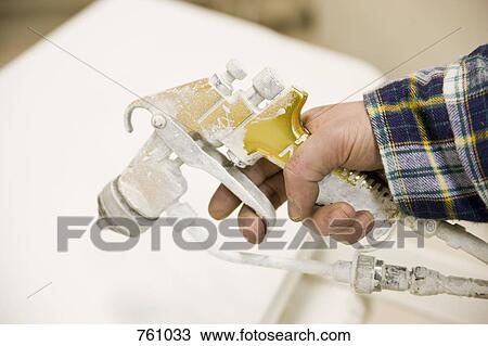 Stock Image - Detail of a man holding a paint spray gun. Fotosearch