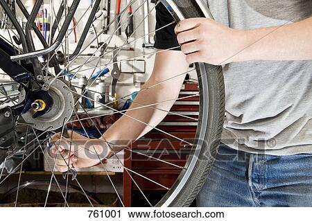 Stock Image - Detail of a man repairing a bike. Fotosearch