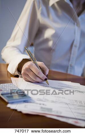 Detail of a young woman writing on a bill View Large Photo Image Stock Photo - Detail of a young woman writing on a bill. Fotosearch