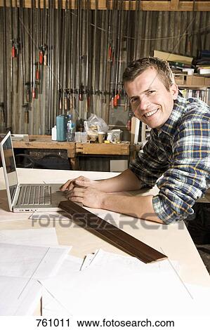 Portrait of a carpenter using a laptop in a workshop View Large Photo Image Stock Image - Portrait of a carpenter using a laptop in a workshop. Fotosearch
