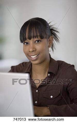 Portrait of a young woman using a laptop View Large Photo Image Stock Image - Portrait of a young woman using a laptop. Fotosearch