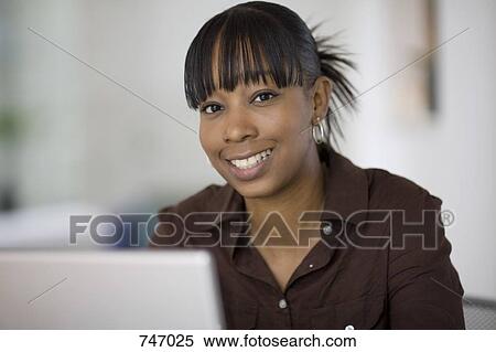 Portrait of a young woman using a laptop View Large Photo Image Stock Photography - Portrait of a young woman using a laptop. Fotosearch