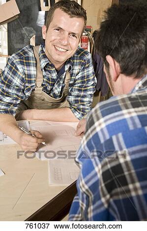 Stock Photo - Two carpenters discussing plans. Fotosearch