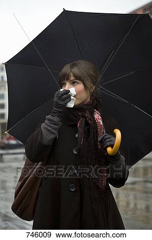 Young woman holding a tissue and an umbrella View Large Photo Image Stock Photo - Young woman holding a tissue and an umbrella. Fotosearch