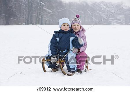 A brother and sister sitting on a sled together tobogganing View Large Photo Image Stock Image - A brother and sister sitting on a sled together tobogganing. Fotosearch