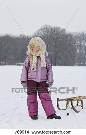 Picture - A girl with a sled, outdoors. Fotosearch