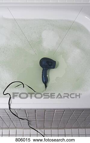 Stock Photography - A hair dryer at the bottom of a full bathtub. Fotosearch