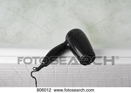 Stock Image - A hair dryer balancing on the edge of a full bathtub. Fotosearch