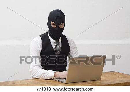 A man wearing a balaclava and using a laptop View Large Photo Image Stock Image - A man wearing a balaclava and using a laptop. Fotosearch