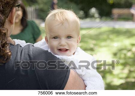 Stock Photograph - A mother carrying her baby girl, over the shoulder view. Fotosearch