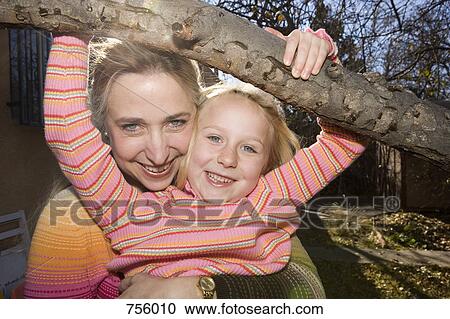 A mother embracing her daughter who is hanging from a tree branch View Large Photo Image Stock Image - A mother embracing her daughter who is hanging from a tree branch. Fotosearch