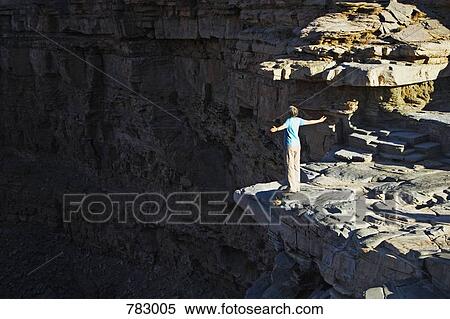 Stock Photography - A person, rear view, standing on the edge of a canyon, Godwana Canyon Park, Namibia. Fotosearch